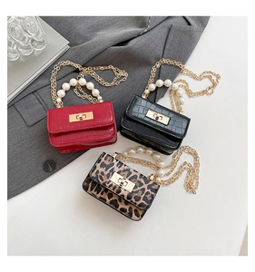 Close-up of crocodile pattern leather textures and luxury pearl handles on mini square bags