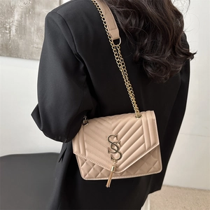 Sac bandoulière beige matelassé avec logo SS doré et pompon sur une veste de blazer noire
