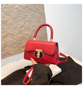 Detail of red leather crossbody bag featuring a distinctive gold and black circular lock