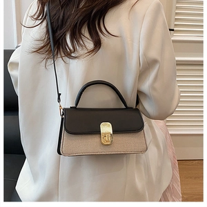 Detail of bicolor crossbody bag featuring straw texture and gold metallic clasp