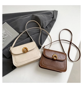 Detail showing vintage U-shaped metal buckles on cream and brown saddle bags