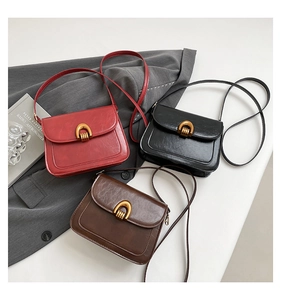 Detailed view of three vintage glossy leather saddle bags with gold horseshoe hardware