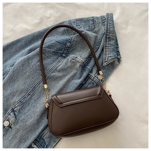 Close-up of a vintage dark brown saddle bag with golden hardware on a denim jacket