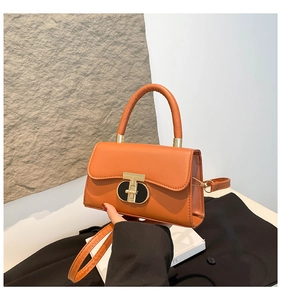 Detail of orange square bag with golden T-lock clasp and round top handle
