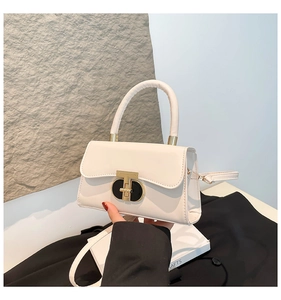 Detail of elegant cream leather crossbody bag with a distinctive gold and black metal clasp