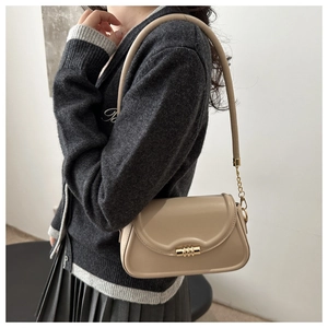 Detail of minimalist beige leather crossbody bag with elegant gold cylindrical lock buckle