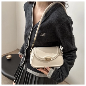 Detail of cream white crossbody bag with gold triple-ring lock and leather chain strap