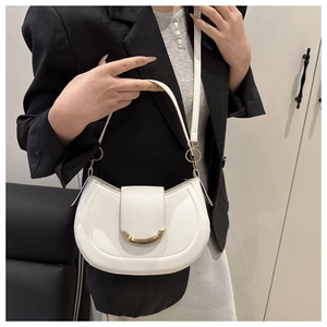 Close-up of ivory moon bag with golden U-buckle detail on model in black blazer