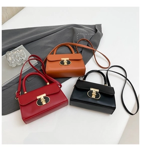 Detail of elegant crossbody bags with gold T-shaped locks in red, brown, and black colors