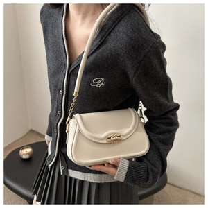 Detailed side view of cream white leather crossbody bag with golden chain strap and lock