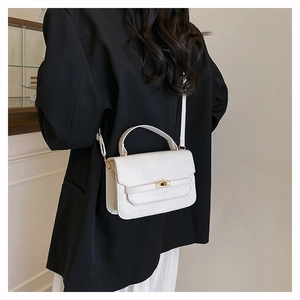White minimalist square crossbody bag featuring a golden twist lock on a black blazer