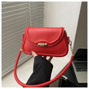 Detail shot of a red minimalist crossbody bag featuring a golden circular lock and strap hook