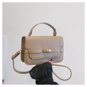 Detail of khaki leather handbag featuring a golden rectangular twist-lock and top handle