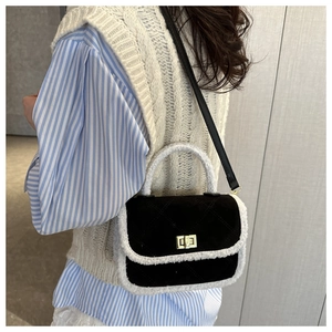 Detail of a quilted black suede bag with white faux fur trim and gold twist lock