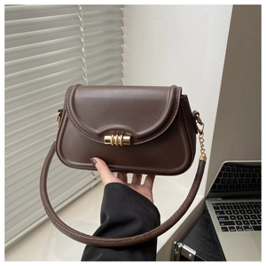 Detail of dark brown leather handbag with gold metal clasp held by a person