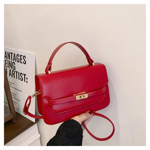 Detailed view of red leather crossbody bag with elegant gold twist lock and top handle