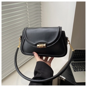 Detail of minimalist black crossbody bag with gold cylindrical metal lock and chain strap