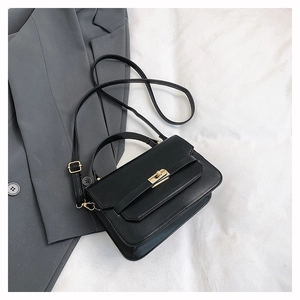 Close-up of black PU leather crossbody bag with golden twist lock on grey blazer background