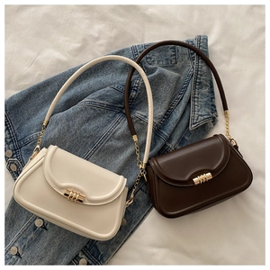 Detail of cream and brown PU leather crossbody bags with gold cylinder buckles