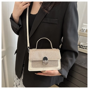 Dettaglio di una piccola borsa a mano quadrata indossata con blazer nero e vestito