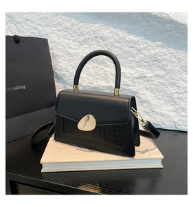 Détail du sac à main noir texture crocodile avec fermoir doré et poignée en cuir chic