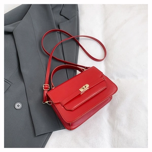 Detail of red faux leather handbag with gold metal twist lock and adjustable strap