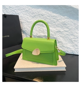Détail du sac vert fluo à motif crocodile avec une boucle dorée en forme de galet unique