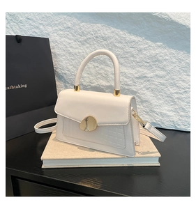 Détail du sac blanc à texture crocodile avec fermoir rotatif galet doré élégant