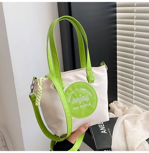 Détail du cabas en nylon contrasté avec broderie verte et bandoulière réglable