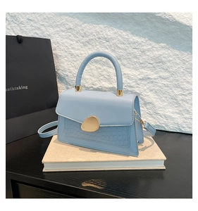 Détail du sac en similicuir bleu clair avec texture crocodile et boucle en métal doré