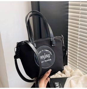 Détail du cabas noir avec surpiqûres contrastées blanches et patch logo rond