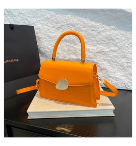 Détail du sac orange texture crocodile avec fermoir métallique en forme de galet