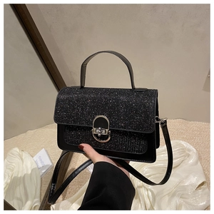 Dettaglio borsa nera glitterata con chiusura metallica ovale argento e manico top