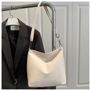 Détail du sac hobo minimaliste crème avec bandoulière réglable et ferrures en bronze fusil