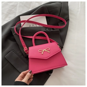 Detail of fuchsia mini crossbody bag featuring a golden bow buckle and PU leather texture