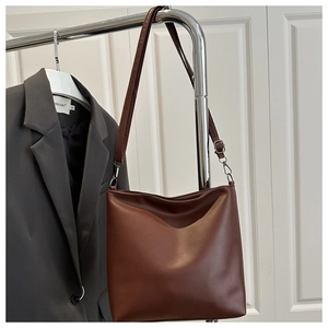 Détail du sac cabas en cuir marron avec bandoulière réglable et plis naturels chic
