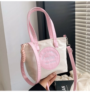 Vue détaillée d'un sac cabas en nylon crème et rose avec broderie et bandoulière réglable