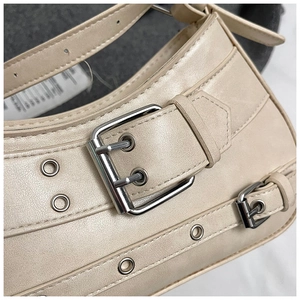 Macro shot of silver buckle and metal eyelets on beige biker style PU leather bag