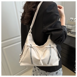 Détail du sac à bandoulière blanc crème avec fermetures éclair décoratives et longs rubans