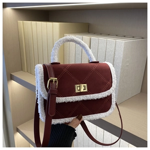 Close-up of wine red quilted bag with white faux fur trim and gold metal hardware