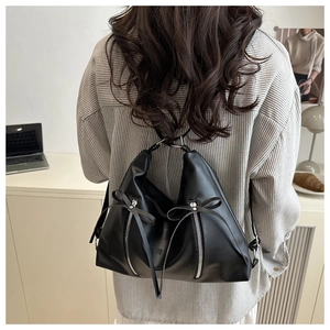 Détail du sac à dos en similicuir noir avec fermetures éclair argentées et nœuds chic