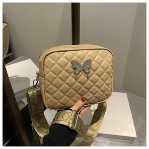 Dettaglio borsa a tracolla beige trapuntata con fibbia a farfalla e tracolla larga