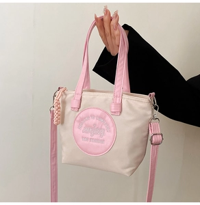 Détail du sac en nylon avec toile beige, finitions en cuir rose et écusson logo
