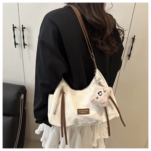 Detail showing cream shoulder bag with brown tassels and pink bear charm decoration