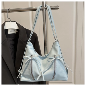Close-up of light blue synthetic leather tote bag with bow ribbons and vertical zippers