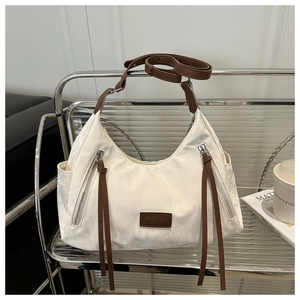 Close-up of cream canvas hobo bag with brown leather trim and long tassel zipper detail