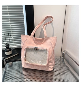 Pink nylon ita bag featuring a clear window and grid pocket on a modern display stand