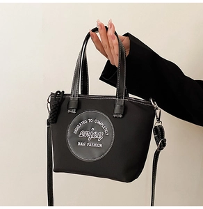 Détail du sac en nylon noir montrant l'imprimé graphique rond et l'accent de sangle tissée