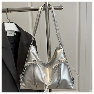 Detail of silver metallic hobo bag featuring dual zippers and decorative ribbon bows