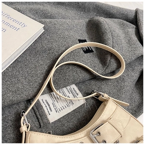 Macro detail of cream motorcycle bag featuring silver buckles and metallic eyelets